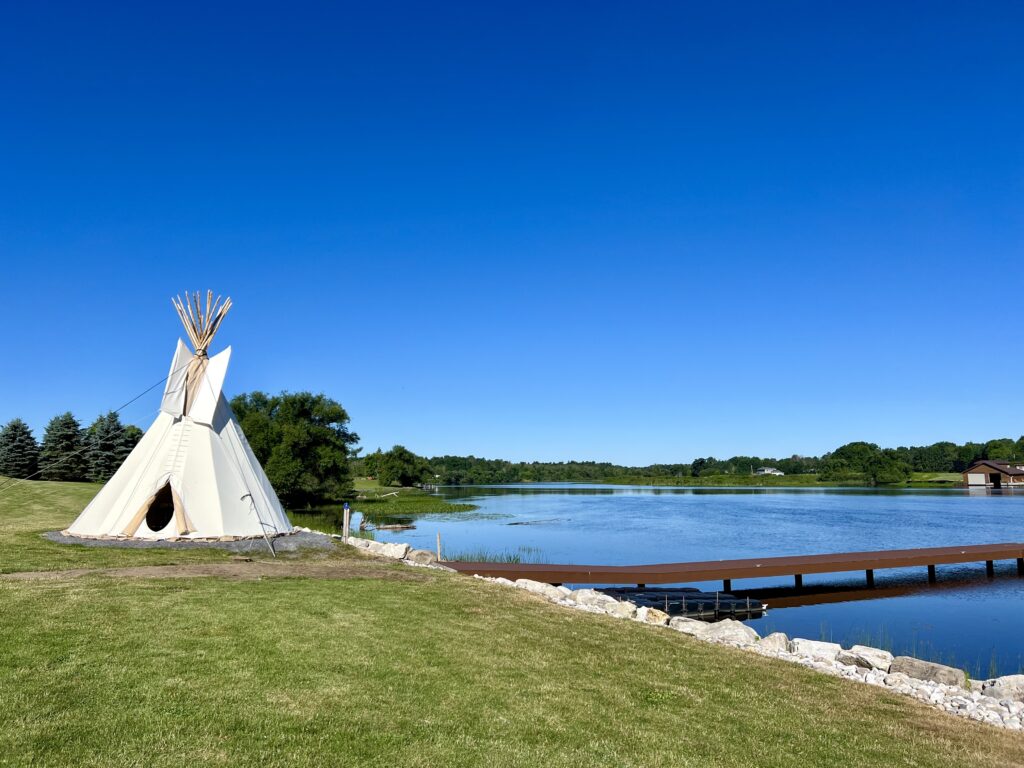 The bright blue sky over Akwesasne and the St. Lawrence river featuring a teepee.